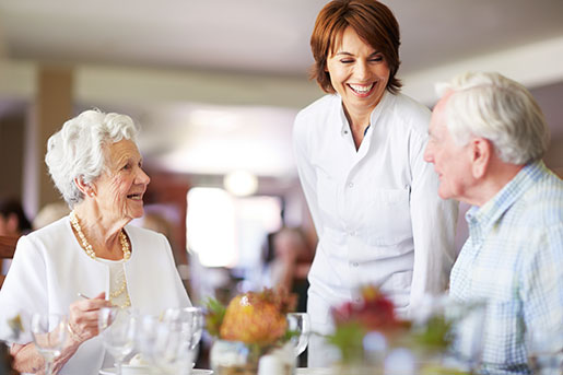 Senior residents chat with a server while dining.