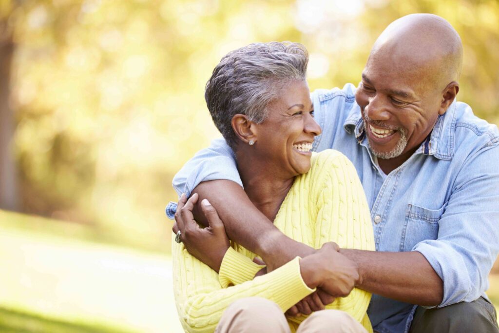 A senior couple smile and embrace for a picture.