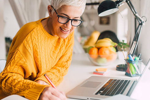 A senior woman working at a desk on a laptop.