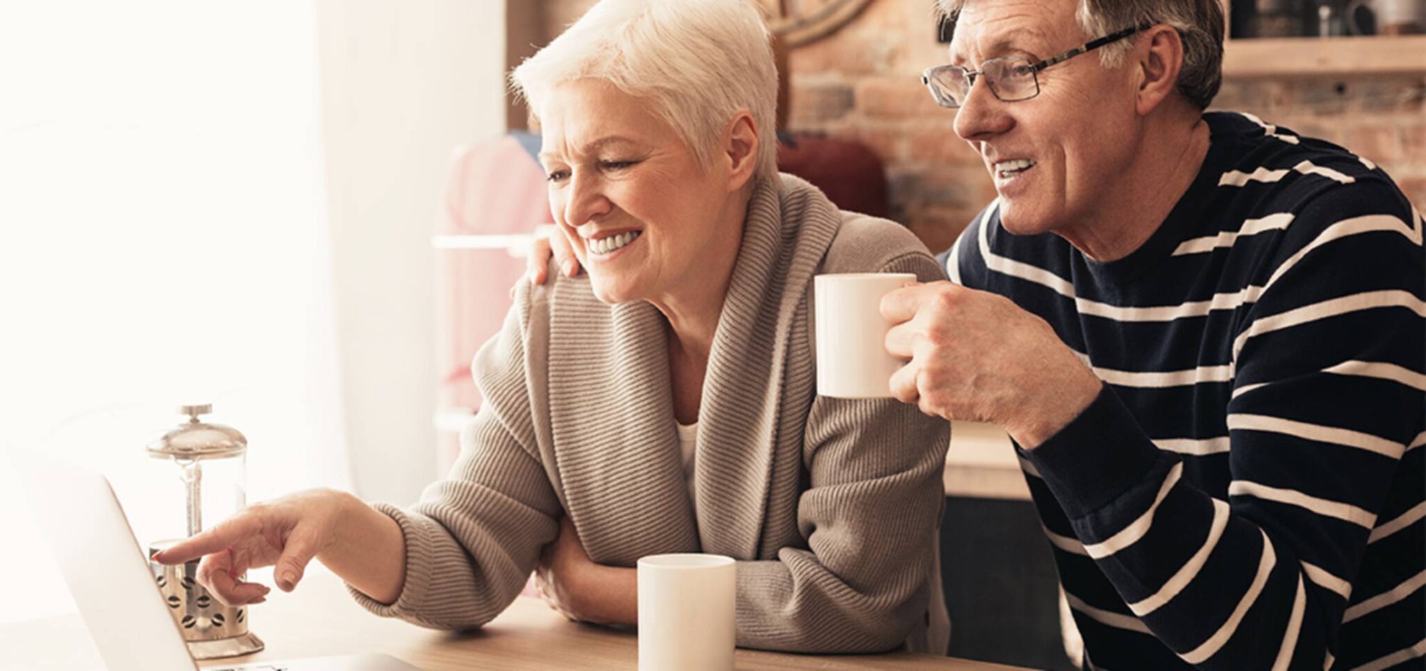 senior couple enjoying their morning coffee while looking at a tablet