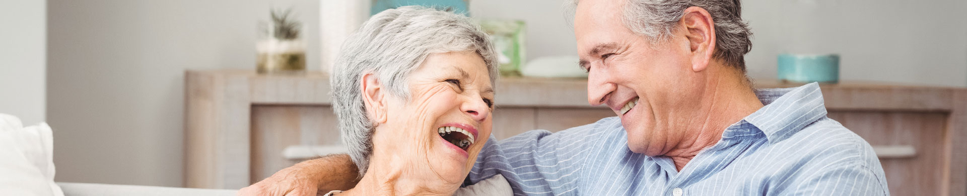 A senior man and woman smile and laugh 
