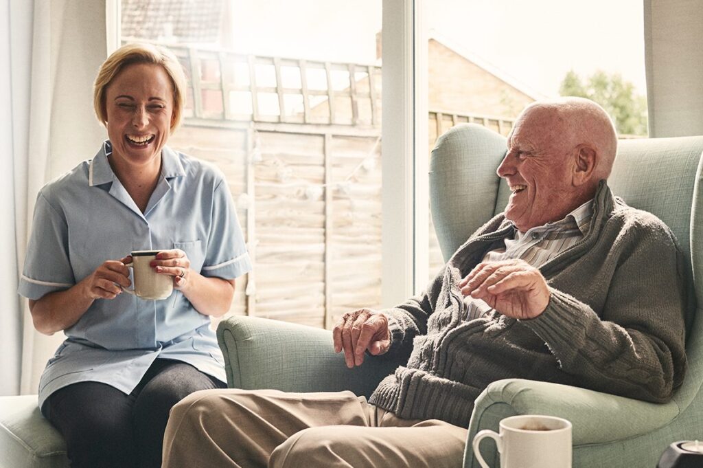 A senior man enjoying coffee with a staff member.