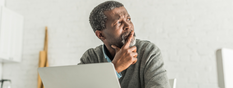 Thoughtful senior man looking away from his computer