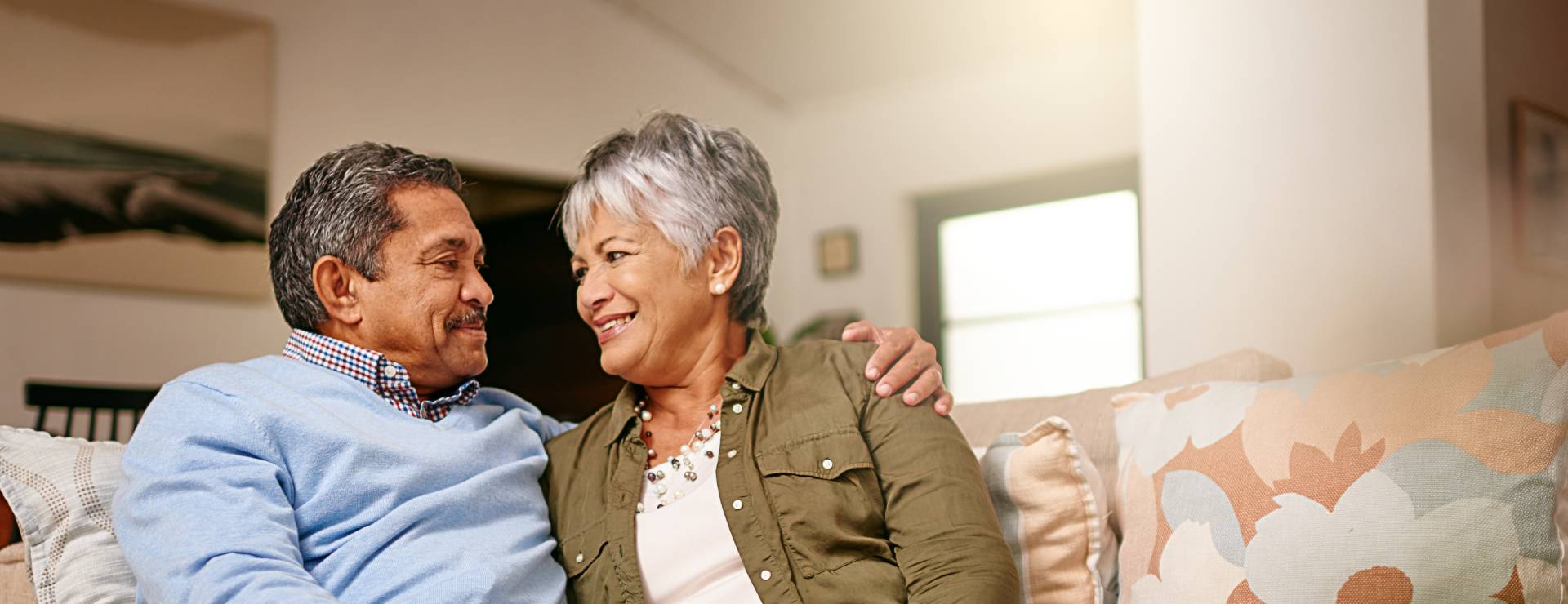 happy senior couple sitting on the couch inside their senior apartment