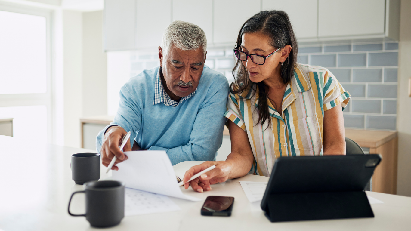 A senior woman points to paperwork and talks to her husband