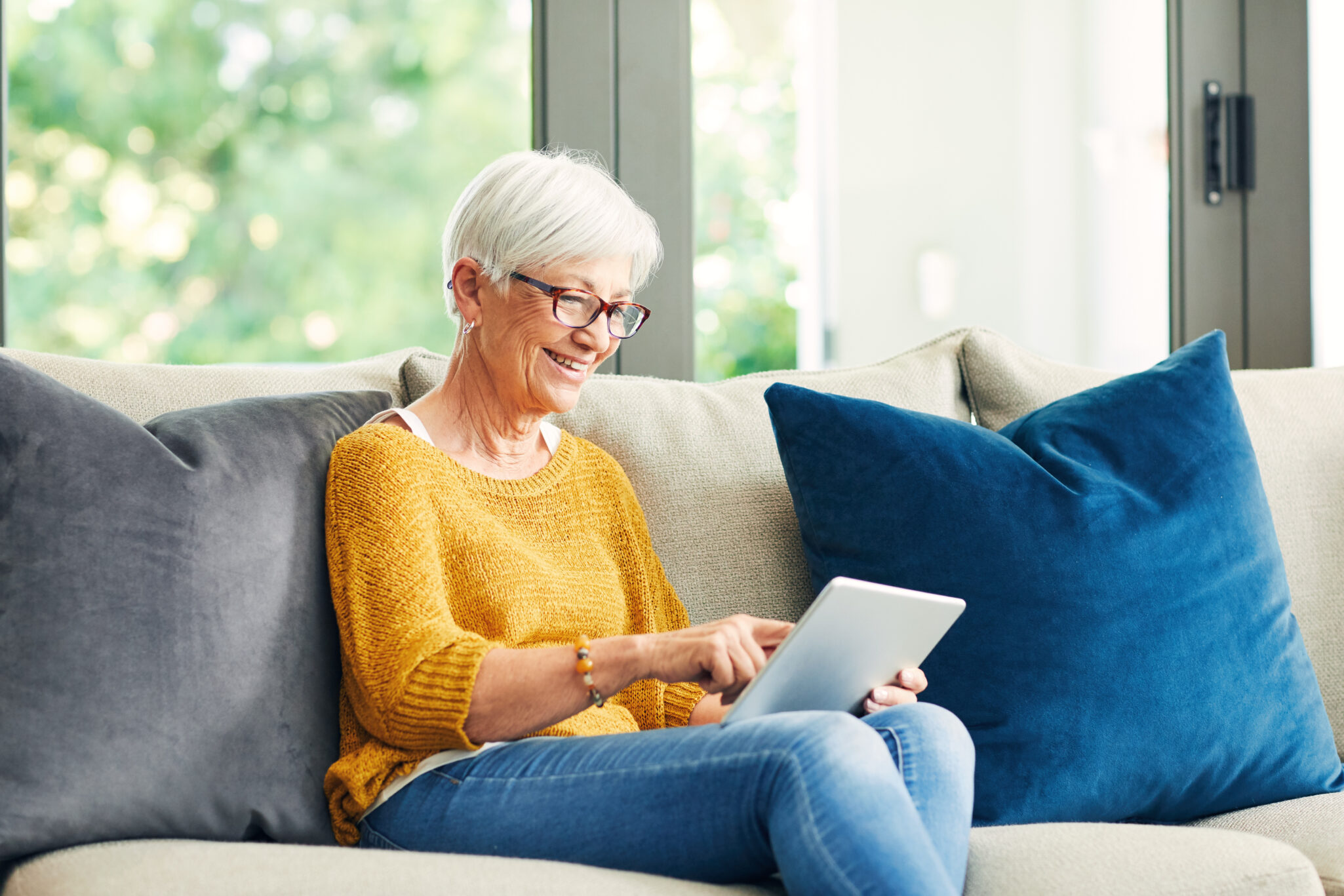 senior woman using a digital tablet on the sofa at home