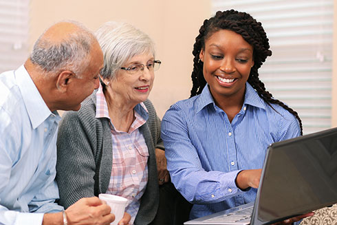 A senior couple look at a laptop with a staff member.