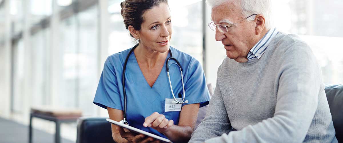 Female skilled nurse talking with senior man about skilled nursing care.