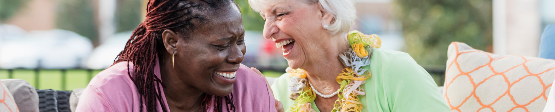 A senior woman laughs with a staff member 