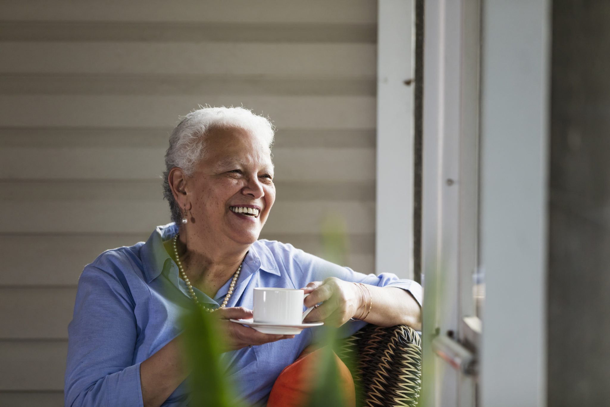 Senior woman holding cup of coffee while looking out a window